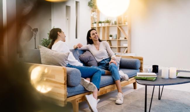 a person sitting on a couch with another woman sitting on the couch